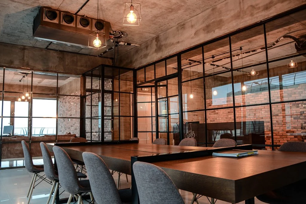 Meeting table and chairs surrounded by exposed brick, concrete and glass