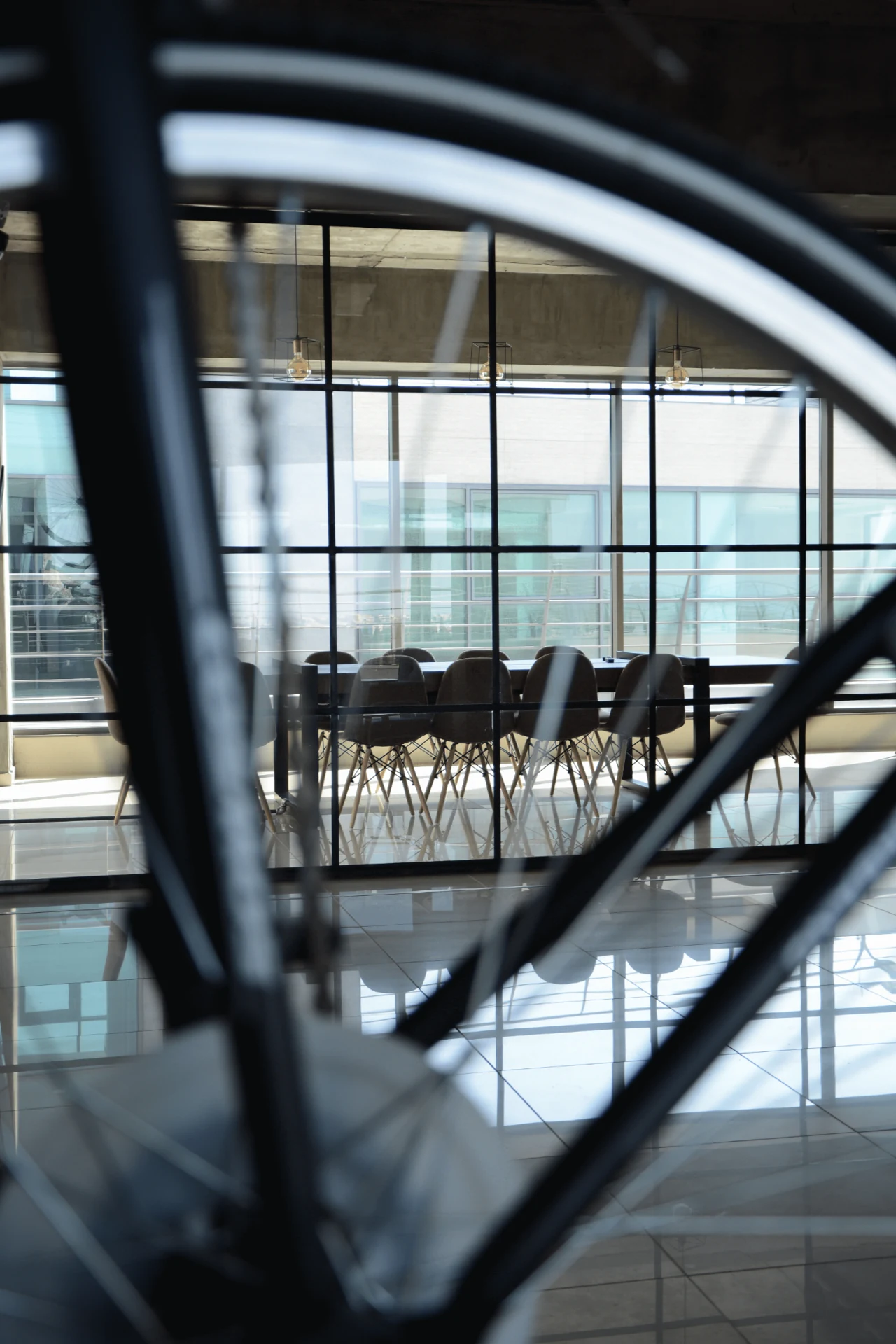 View through a bicycle wheel toward the glass-walled studio meeting room