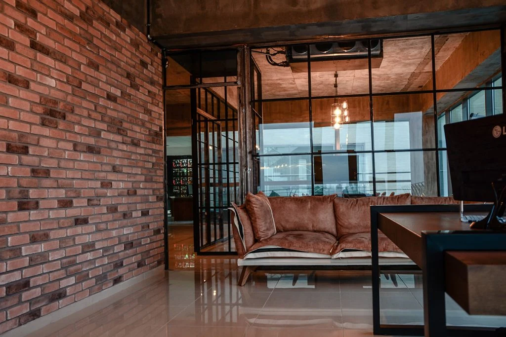 Sofa and meeting space beside exposed brick and glass partitions